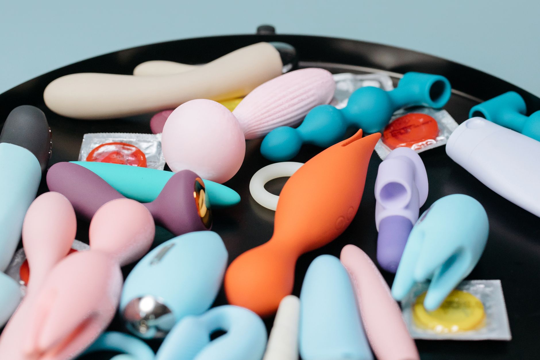 Close-up of colorful clitoral vibrators and intimate wellness toys on a black surface