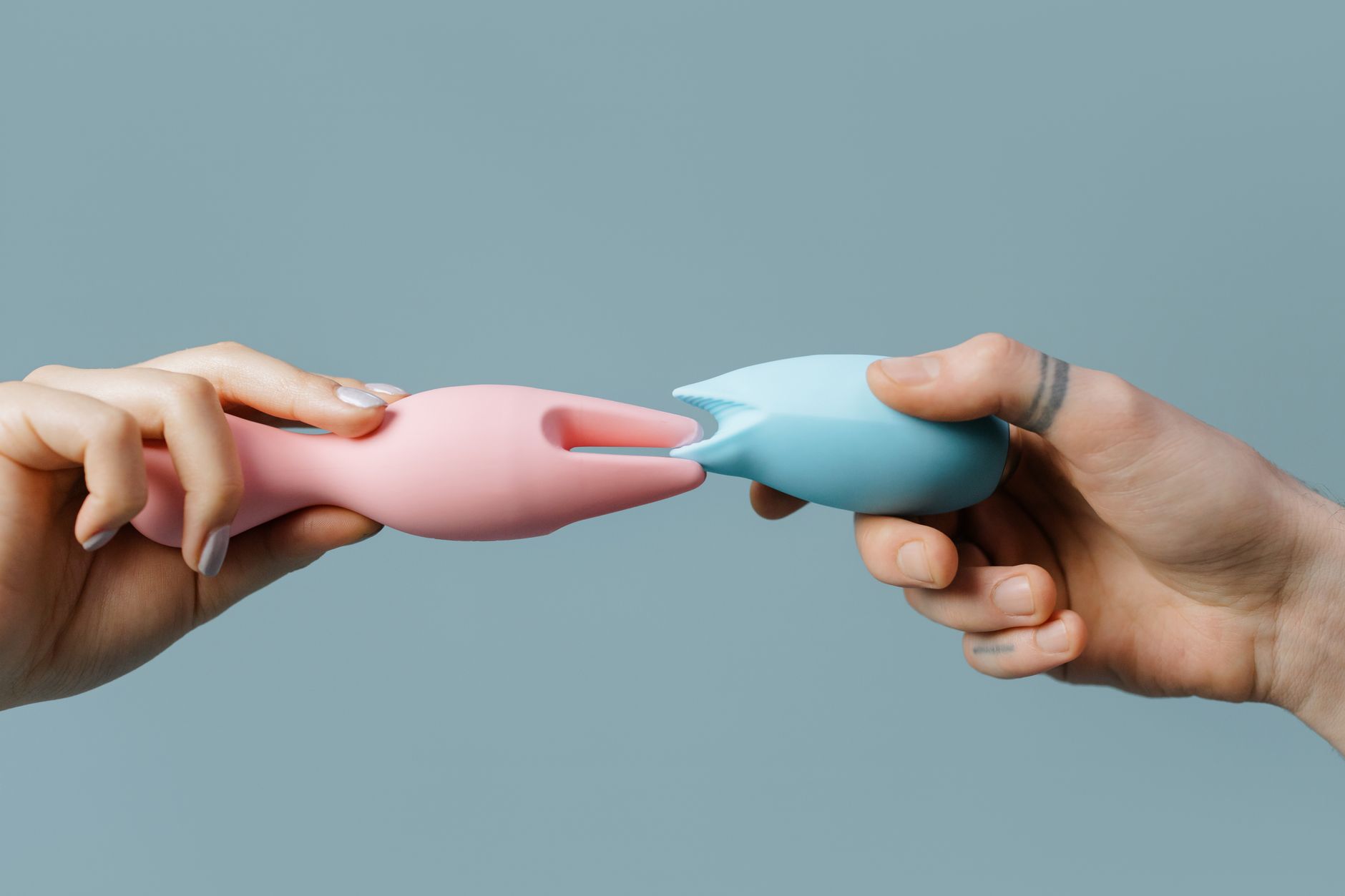 Close-up of hands holding a sleek vibrator, showing intimate connection and intentional touch