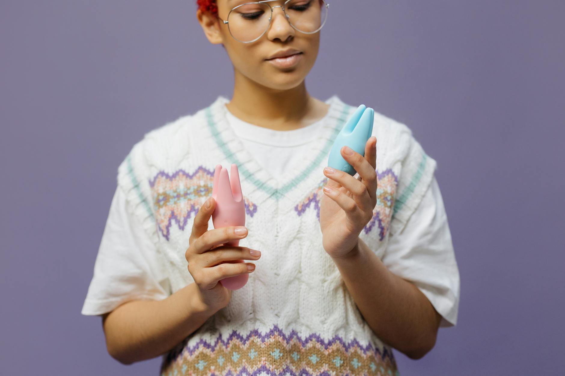 Woman examining pleasure devices thoughtfully in neutral light