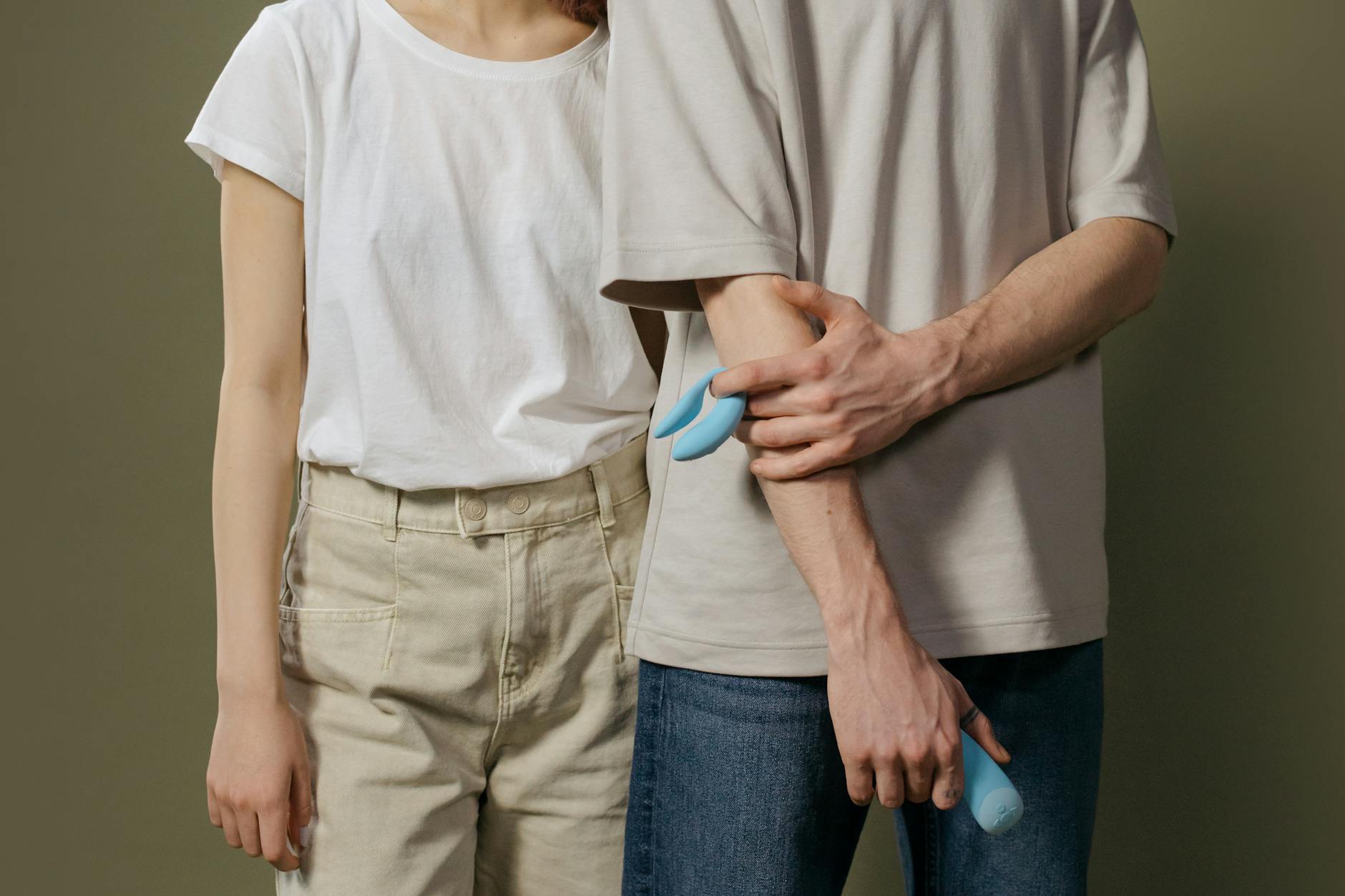 A couple standing together indoors, introducing a blue vibrator into their intimate life